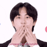 a young man is covering his mouth with his hands and the words jungwon solo de katsita are written below him