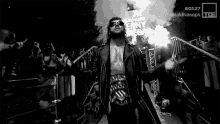 a black and white photo of a wrestler walking out of the ring .