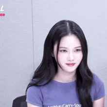 a woman with long black hair is wearing a purple shirt that says archive-carry-souv