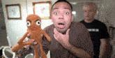 a man is holding a stuffed animal in front of another man wearing a shirt that says ' s in the ga '