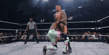 a wrestler in a pink and green outfit is being pinned by another wrestler in a wrestling ring
