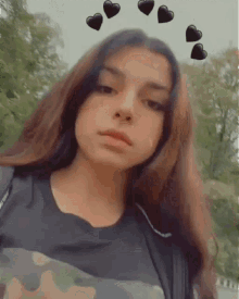 a young girl with long hair is taking a selfie with hearts on her head .
