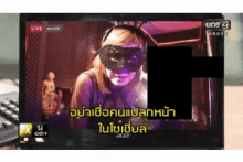 a screen shows a woman wearing a mask and headphones and says live on the top left