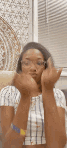 a woman wearing glasses and a nose ring is making a funny face with her hands .