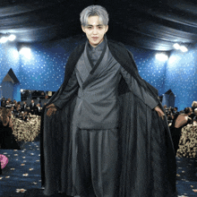a man in a gray suit and black cape