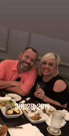 a man and a woman are sitting at a table with plates of food and drinks on july 28th 2019
