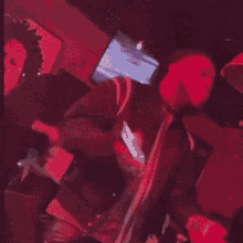 a man in a red jacket is standing in front of a television .