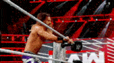 a wrestler is standing in a wrestling ring with a rope around his neck .
