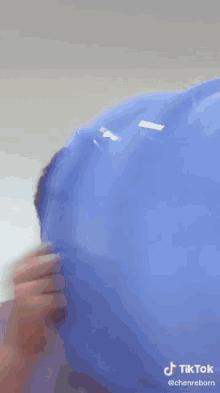 a man in a purple shirt is holding a blue balloon in his hand and smiling ..