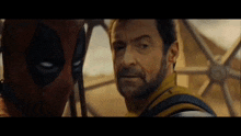 wolverine and deadpool are standing next to each other and looking at each other in a movie .