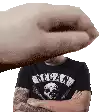 a man wearing a black shirt with a skull on it is being slapped by a hand .