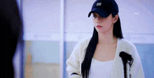 a woman wearing a black hat and a white sweater is standing in front of a mirror .