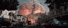 a large explosion is taking place in a city with a church in the background .