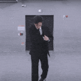a man in a suit and tie is standing in a room with a fire alarm on the wall