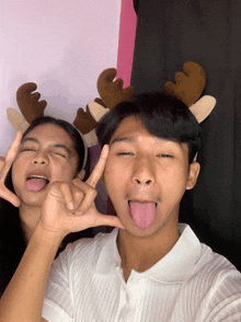 a boy and a girl wearing reindeer antlers make a peace sign