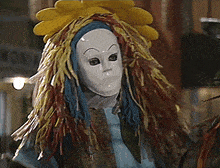 a person wearing a white mask with a yellow flower on top