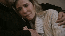 a man is hugging a woman who is crying and holding her shoulder .