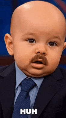 a baby is wearing a suit and tie and has a mustache