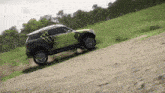 a monster energy mini cooper is driving down a dirt road
