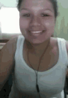 a woman in a white tank top is smiling