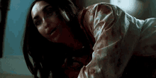 a woman with blood on her shirt is laying on the floor .