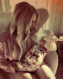 a woman is holding a baby in her lap and the baby is wearing a floral hat