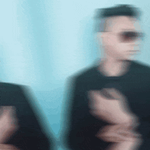 a blurry image of a man wearing sunglasses and a black shirt