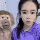a woman in a purple shirt is taking a picture of herself and a monkey .