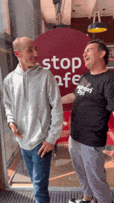 two men standing in front of a sign that says stop afe