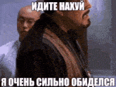 a man with a beard stands in front of another man with a foreign language caption