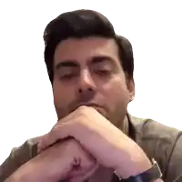 a man with his hands folded on his chin looks at the camera