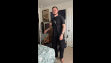 a man is dancing in a bedroom with a picture of a baseball field on the wall behind him