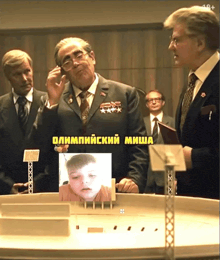a group of men are standing around a table with a picture of a child on it and the words olympics on it
