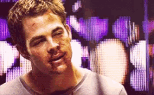 a man with blood on his face is smiling in front of a purple background