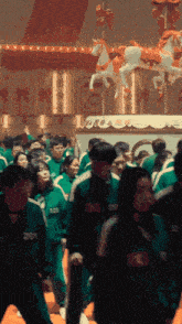 a crowd of people are standing in front of a merry go round with a horse on top