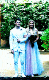 a man in a white suit stands next to a woman in a blue and purple dress