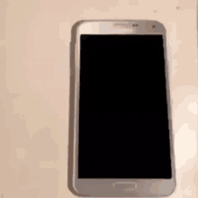a white cell phone with a black screen is sitting on a white surface