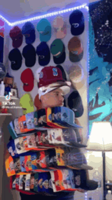 a man is standing in front of a wall full of hats including one with the letter s on it
