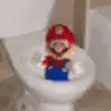 a mario figurine is sitting on a toilet .