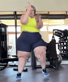 a woman is dancing in a gym wearing shorts and a yellow tank top