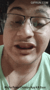 a man wearing glasses and a green shirt is making a funny face