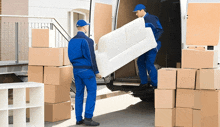 two men carrying a white couch out of a van