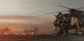 a group of soldiers are standing next to a helicopter .