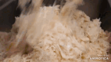 a pile of shredded cabbage is being mixed in a bowl with a spoon .