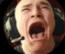 a close up of a man 's face with his mouth open and headphones on .