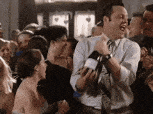 a man in a tie is dancing in a crowd of people at a party .