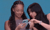two women are looking at a cell phone and one has a watch on her wrist