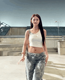 a woman wearing a white crop top and jeans is walking