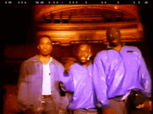 three men in purple jackets are standing next to each other in front of a building