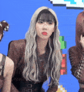 a woman with long blonde hair and red lips is standing next to another woman